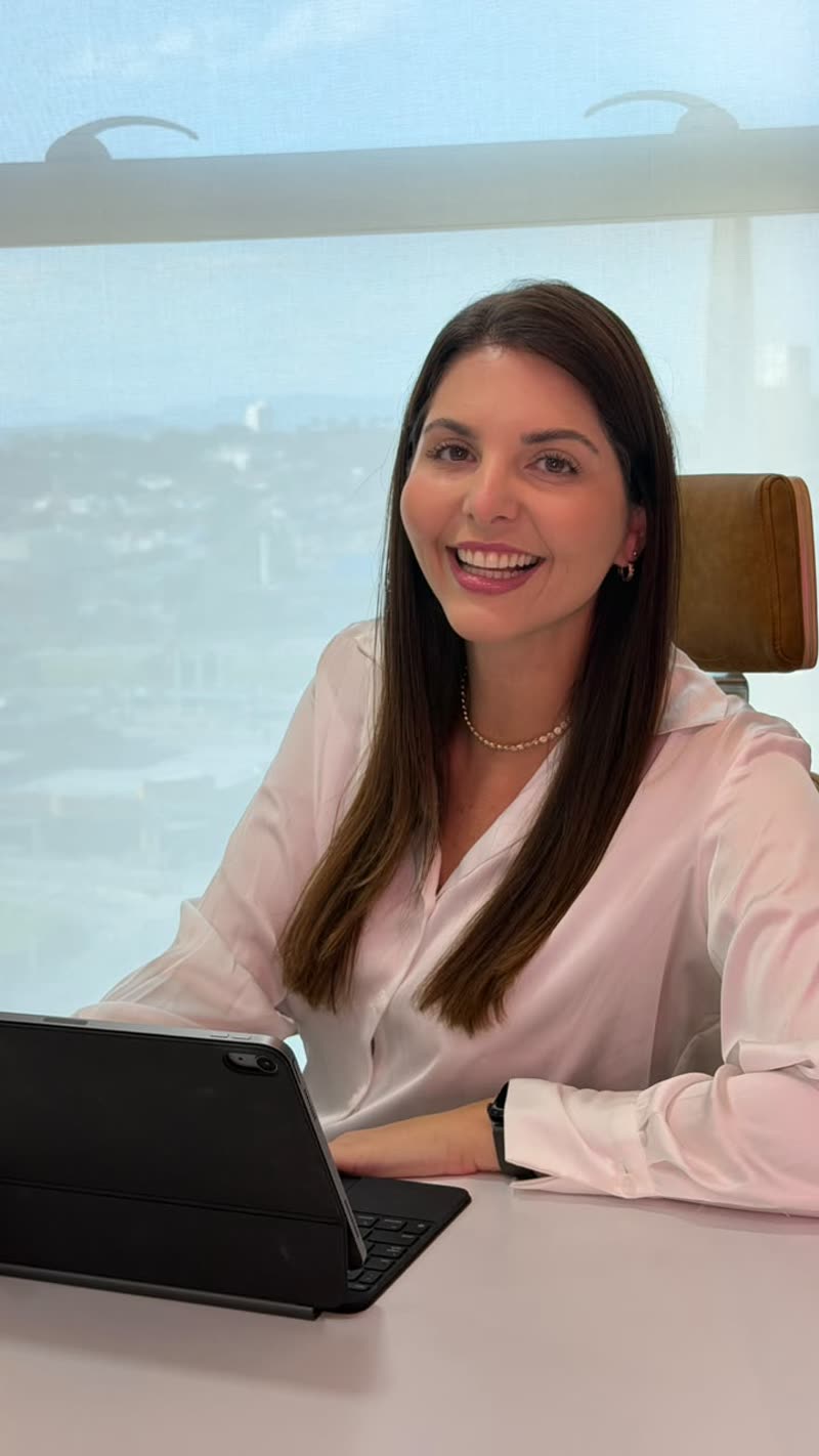 Dra. Raiane Alponte, da Clínica HARA, sorrindo à mesa do consultório com um tablet